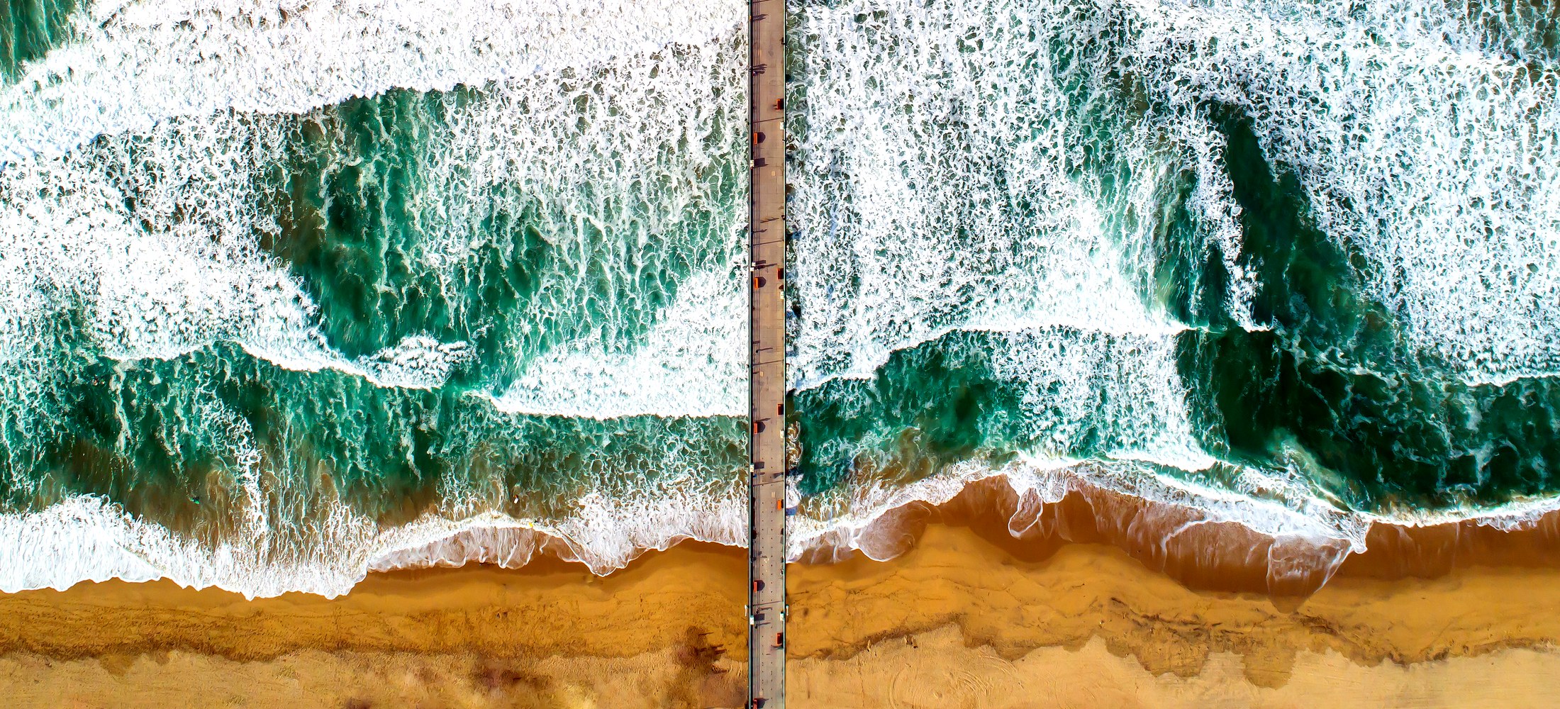 Aerial view straight down the Manhattan Beach Pier and Roundhouse, with the Sand Section and South Bay coastline beyond